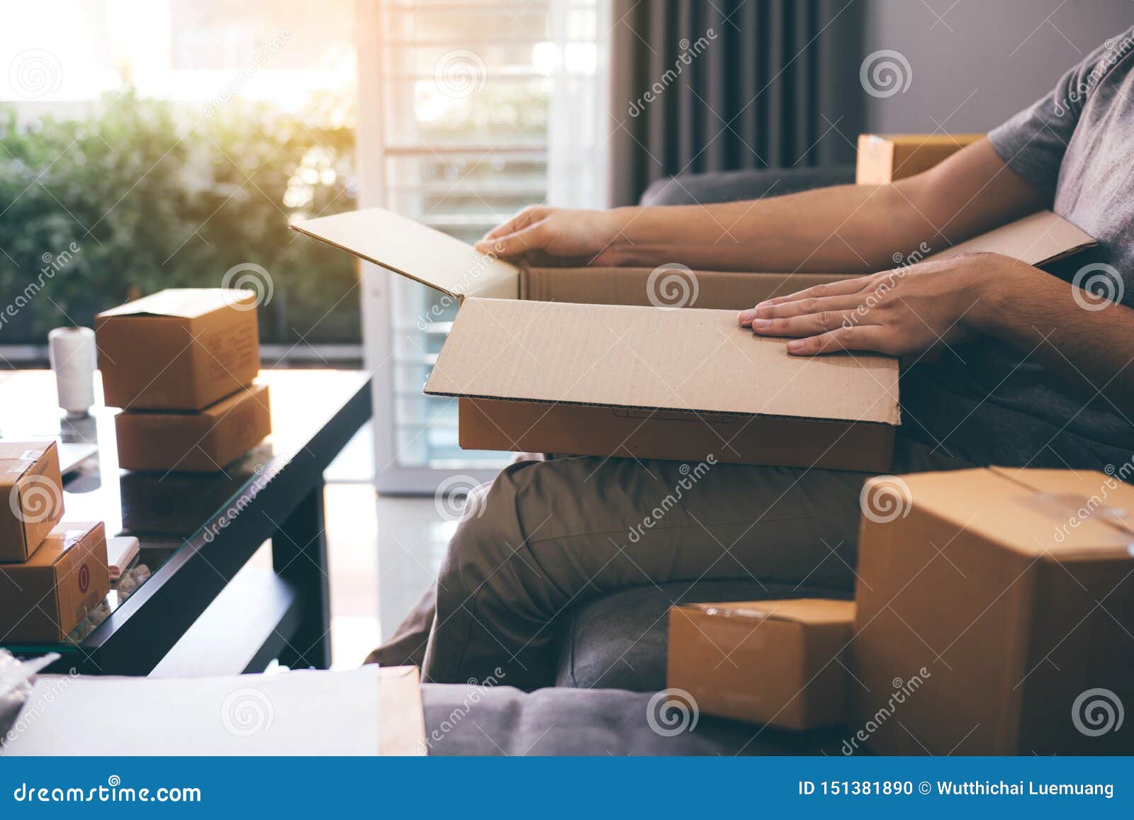asian entrepreneur teenager is opening a cardboard box in order to put the product that the customer ordered into the box to