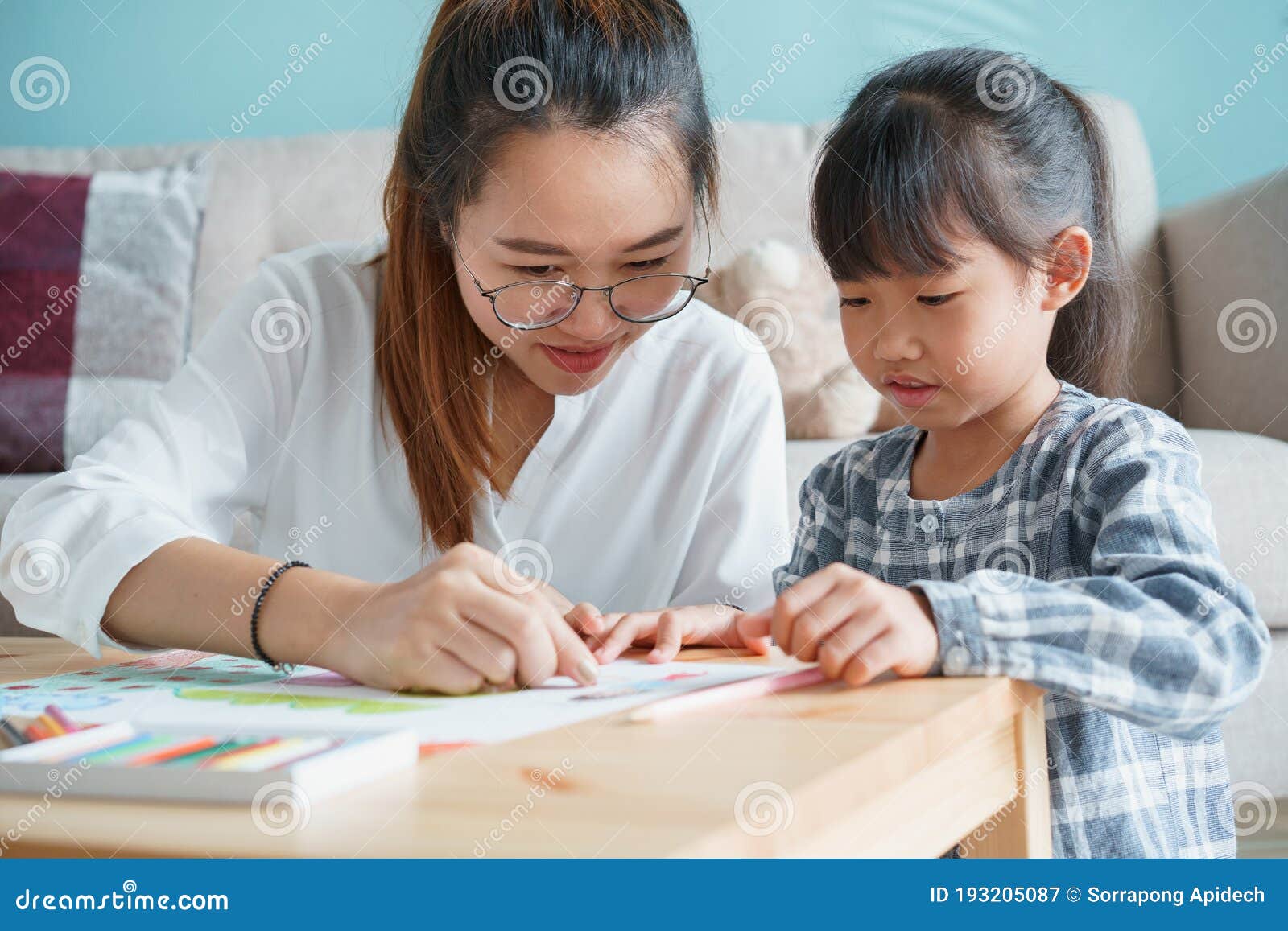 asian family with mother and daughter doing together activities at home. happy mom and child doing learning and drawing on table
