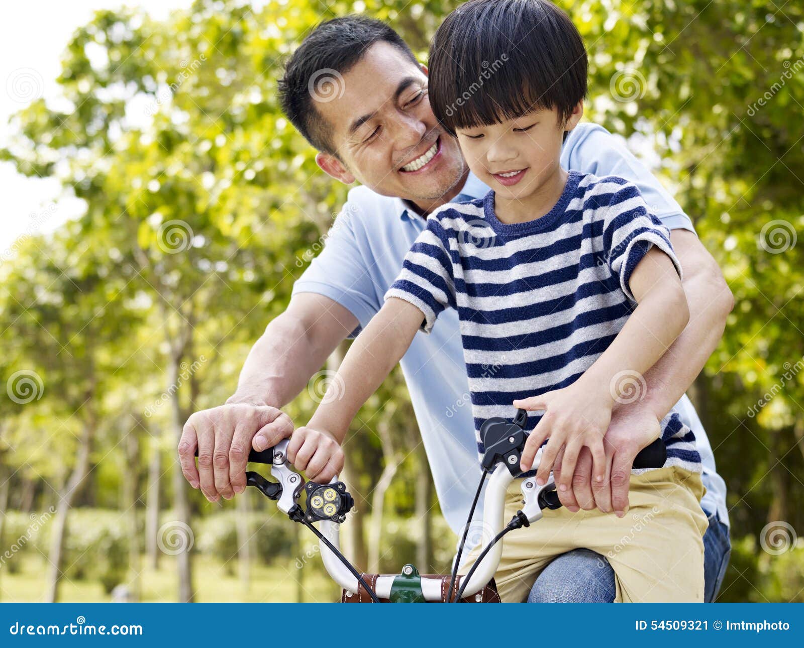 asian father and son enjoying biking outdoors