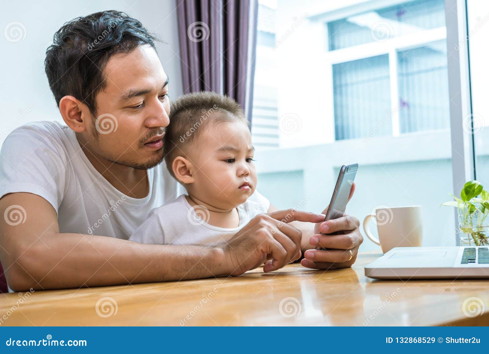 asian father and son using smart phone together in home background. technology and people concept. lifestyles and happy family th