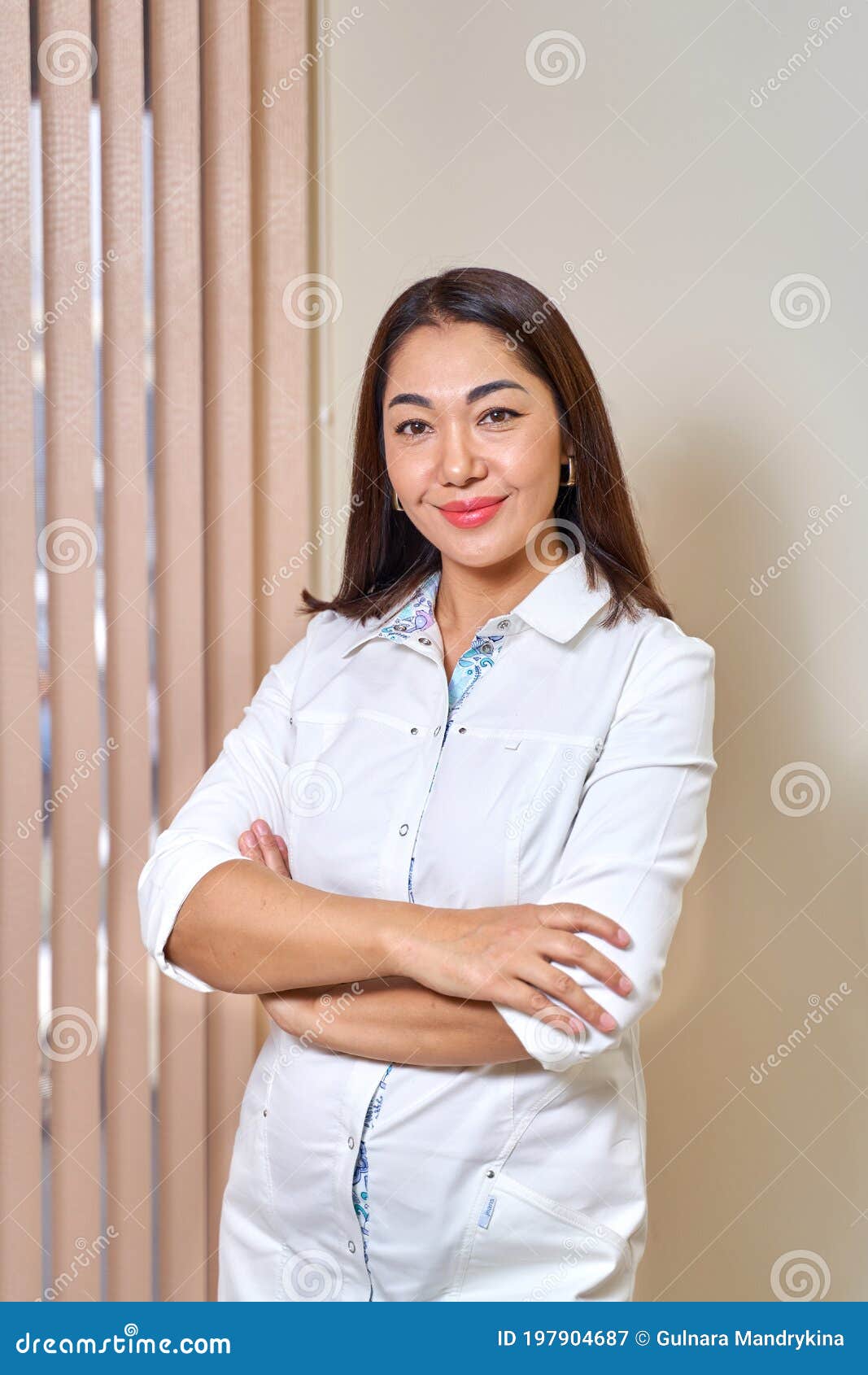 Asian Female Doctor in White Coat Looks into the Frame Stock Image