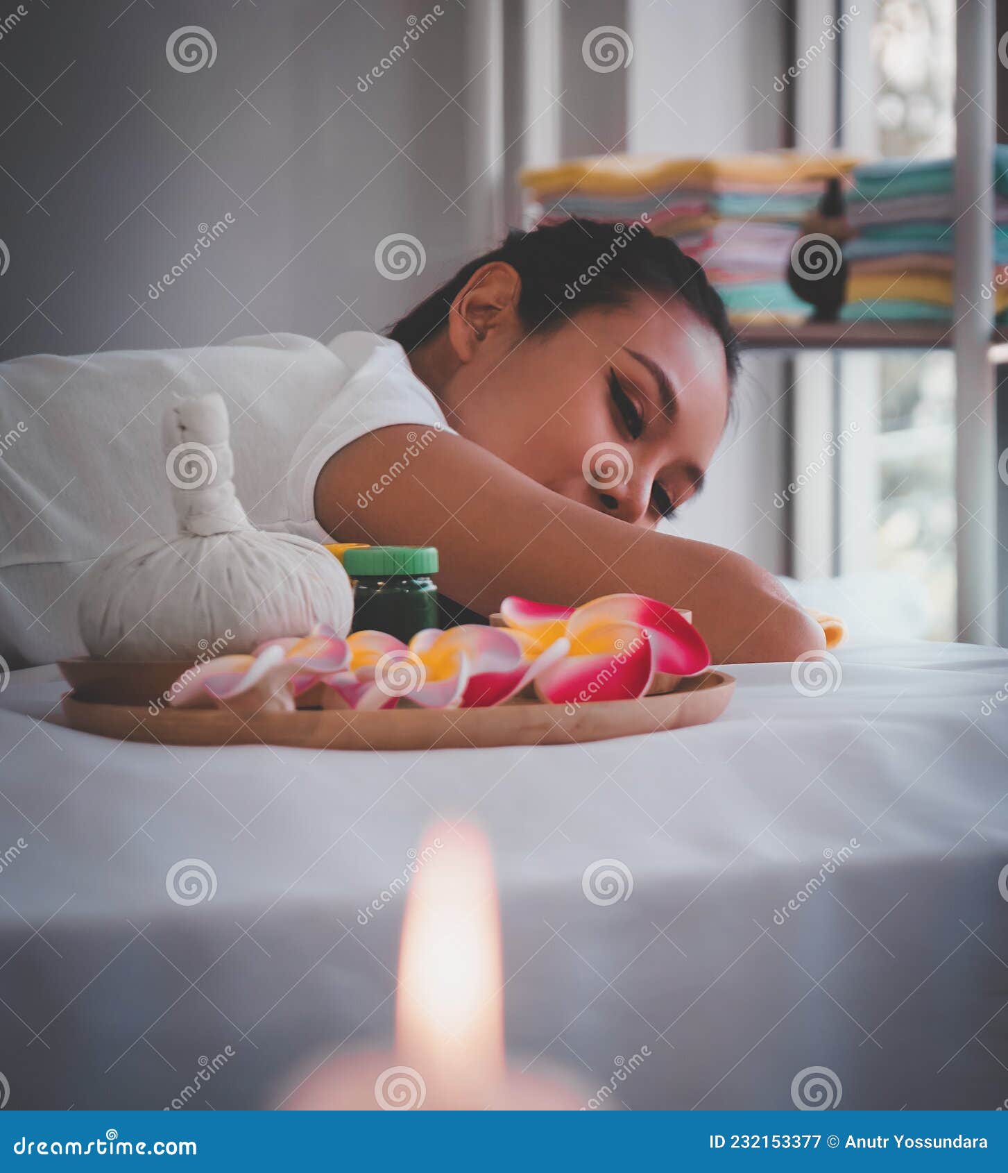 asian female relaxing in thai spa with flower and hot compressed anc candle
