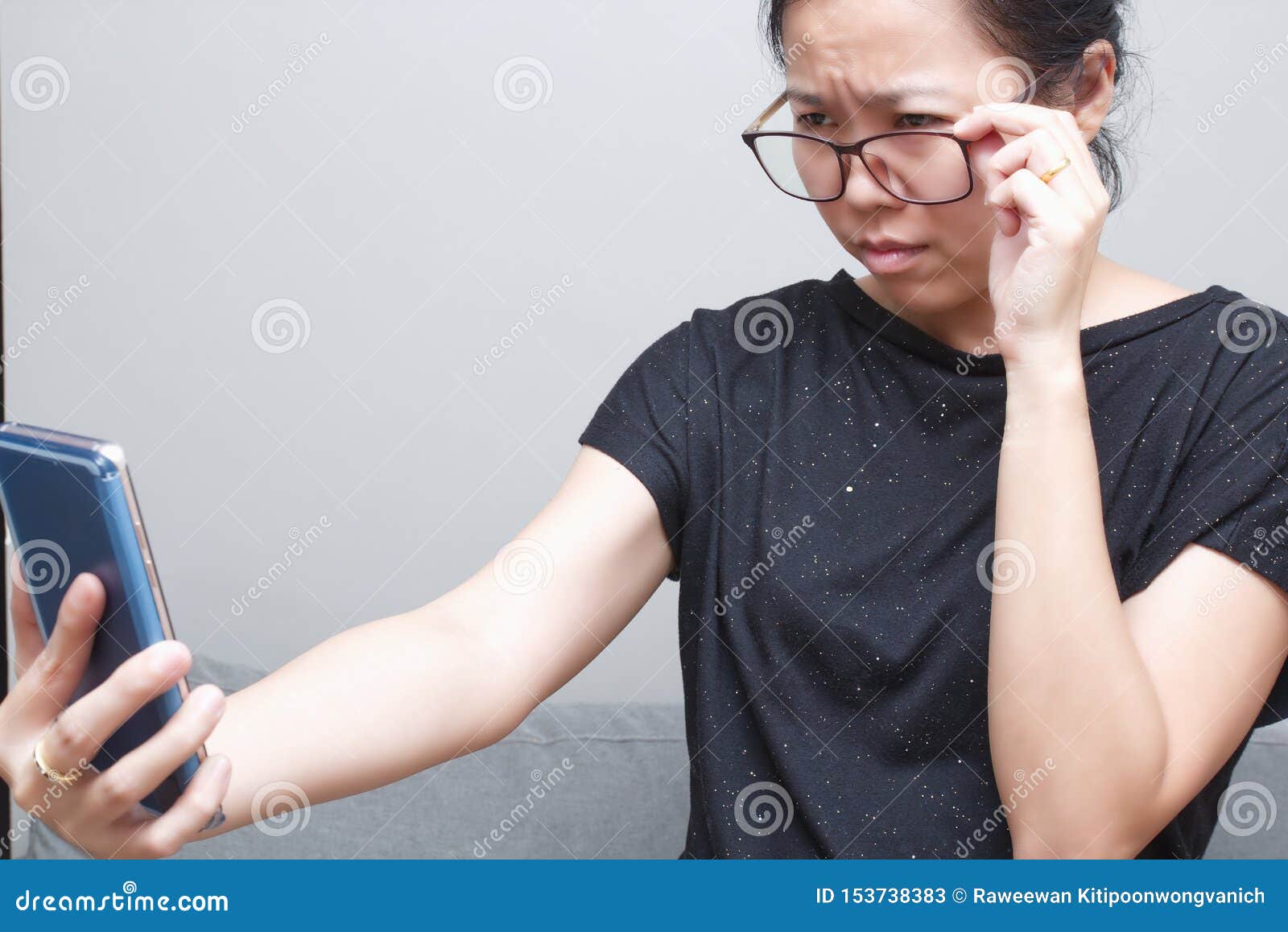 asian female trying to read something in her mobile phone. poor sight, farsightedness, myopia