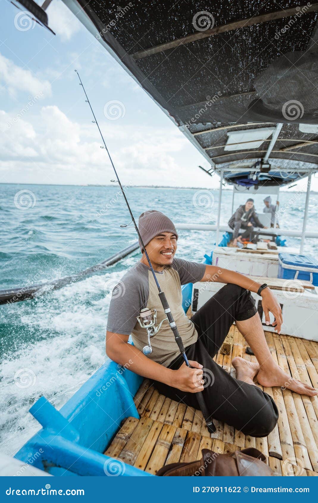 Asian Fisherman Sitting on a Fishing Break on a Boat Stock Photo