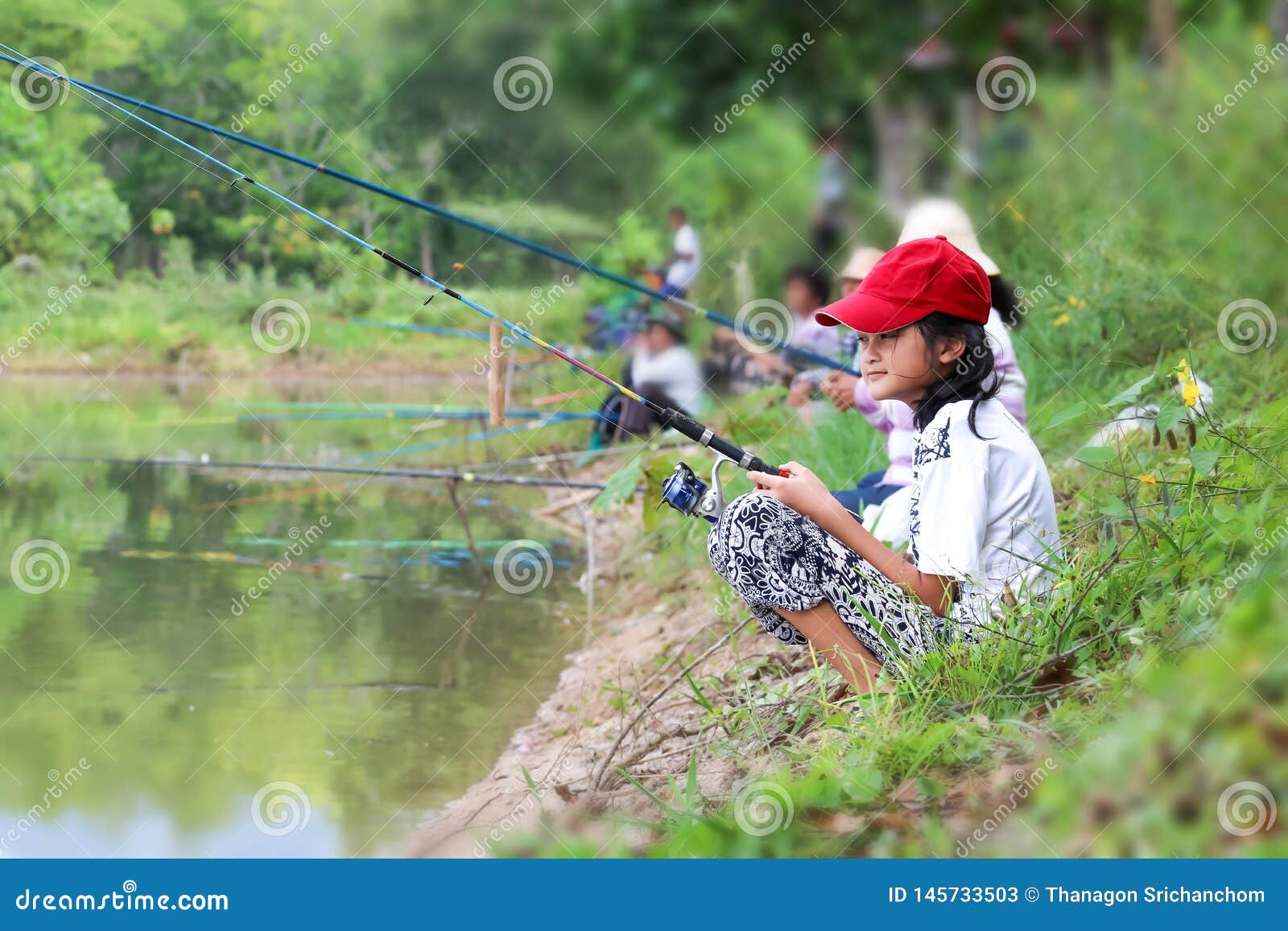 Asian Girl Enjoying To Use a Fishing Rod by the Canal or River