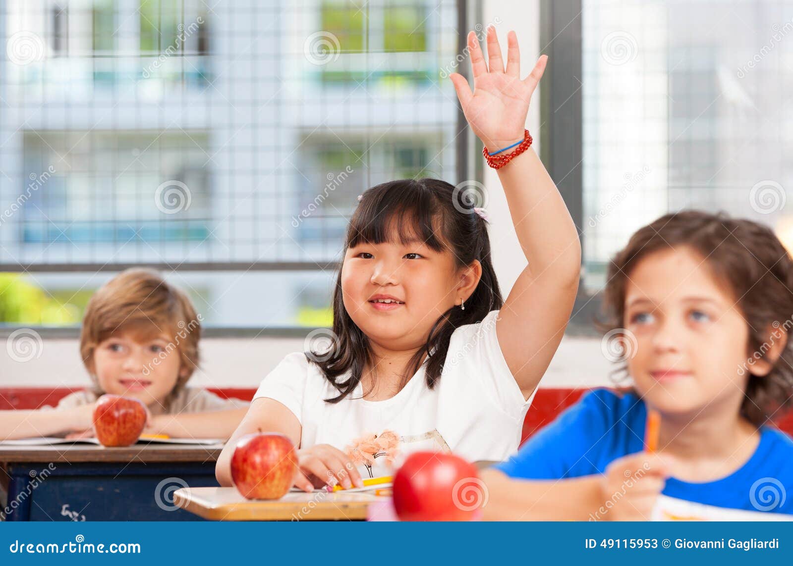 asian girl raising hand in multi ethnic ary classroom