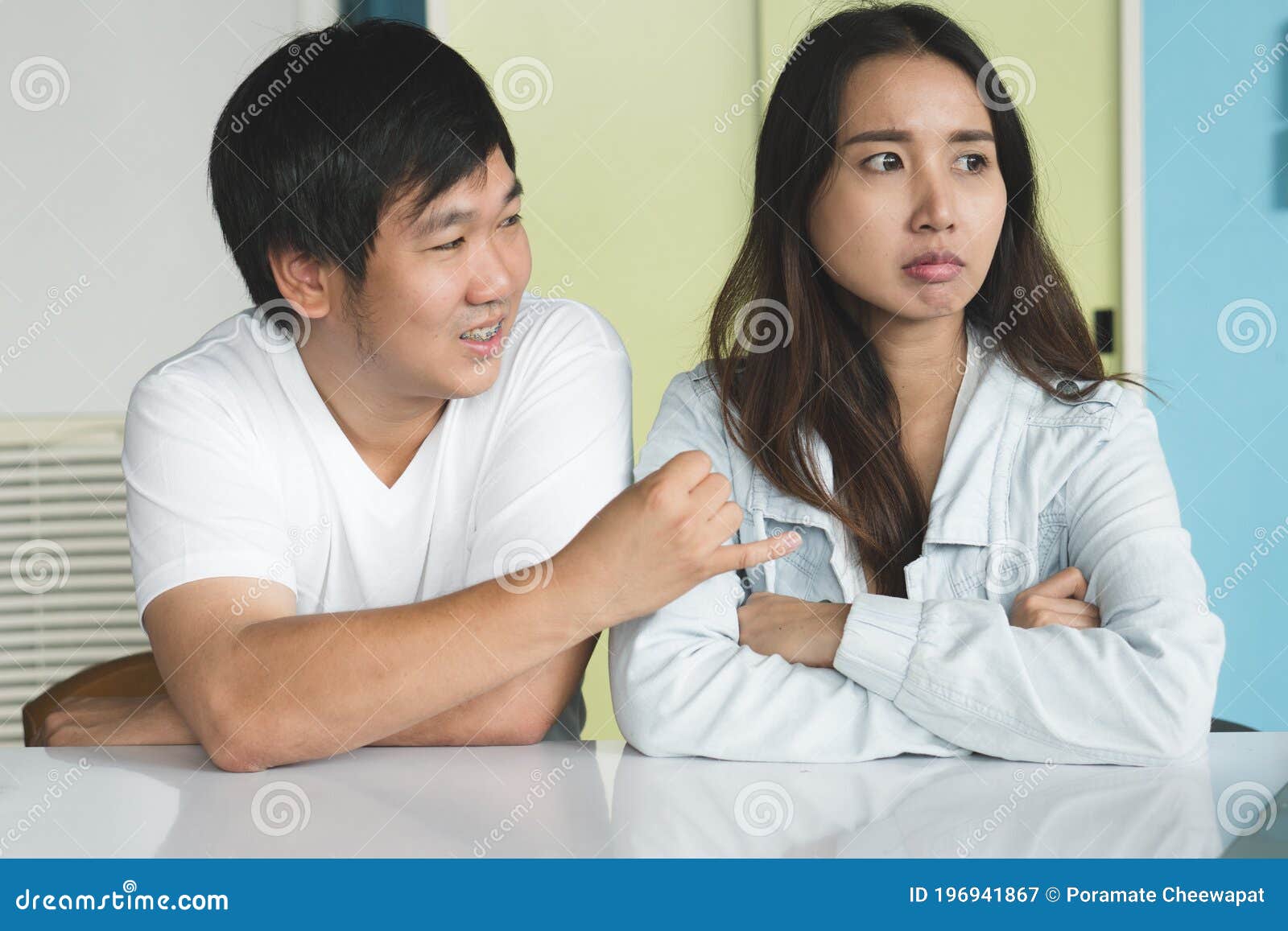 Asian Young Girl Friend Angry At Boyfriend Playing Online Game On Computer.  Mad Female Pushing Guy And Scolding At Him. Frowning Man Ignores His  Annoyed Lover And Wearing Headphones Keep Having Fun.