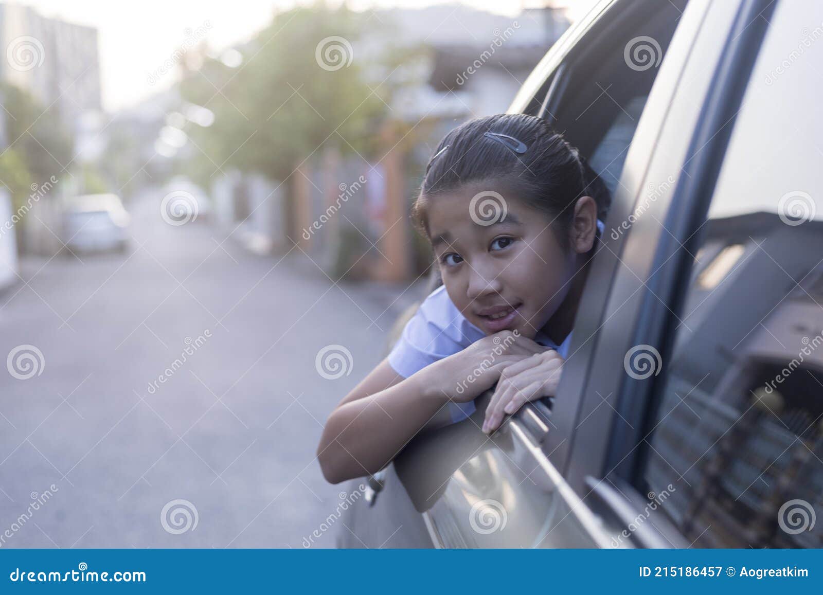 asian happy student smiling with camera while enjoying road trip in car. daughter smiling and looking camera inside car in morning