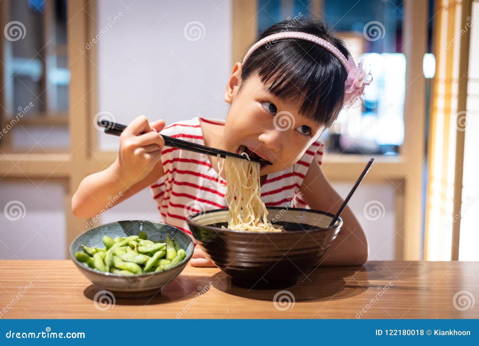 a little girl eating noodles