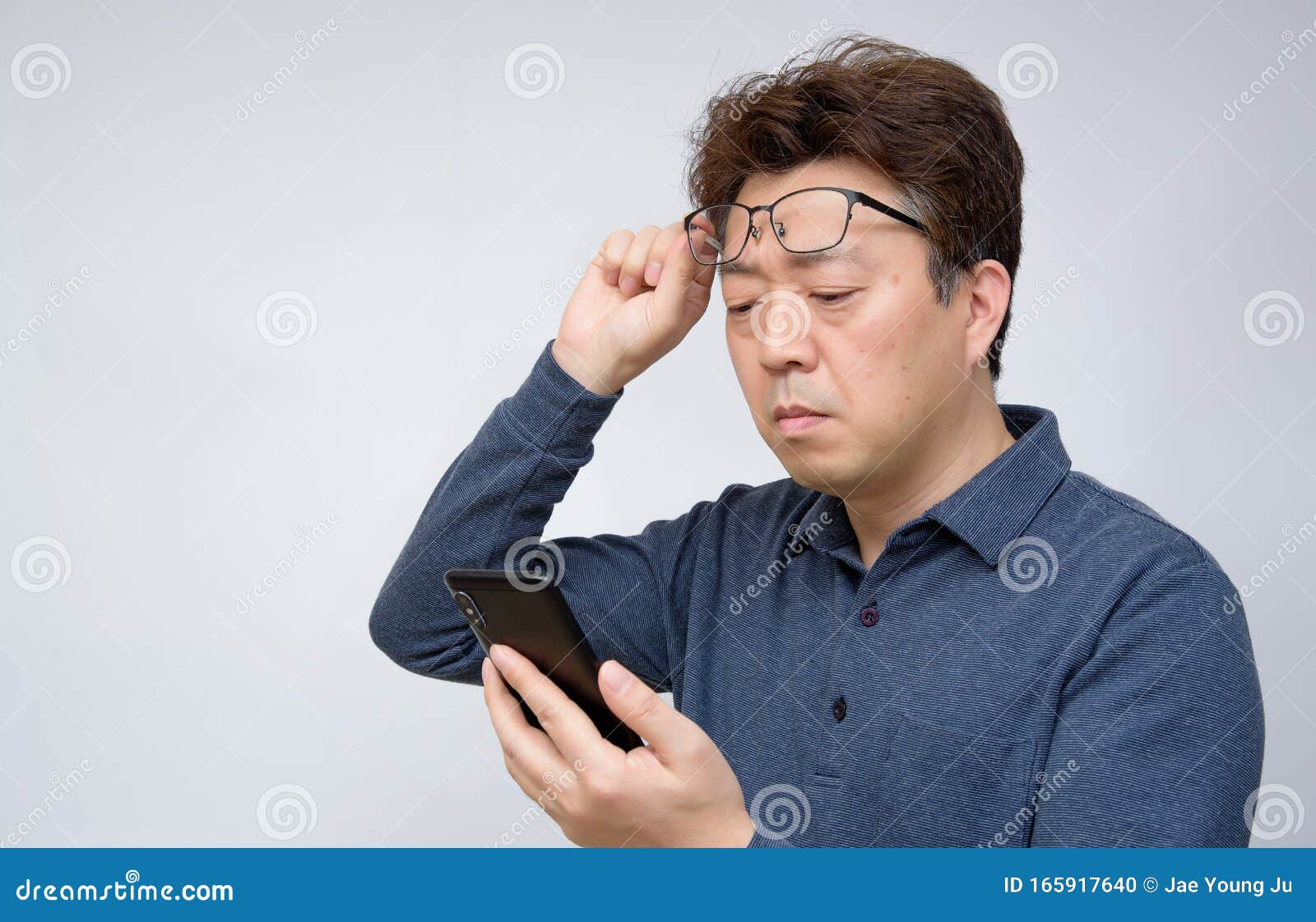 asian male trying to read something on his mobile phone. poor sight, presbyopia, myopia.