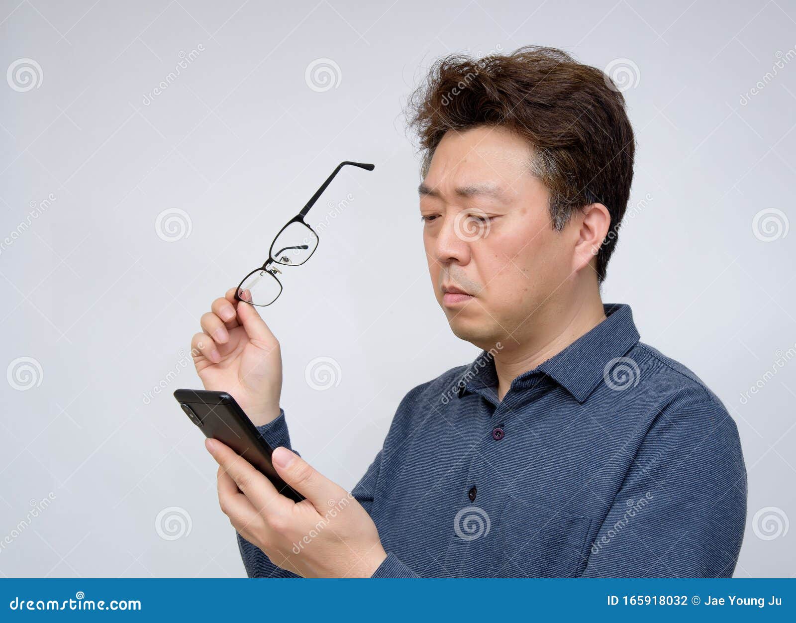 asian male trying to read something on his mobile phone. poor sight, presbyopia, myopia