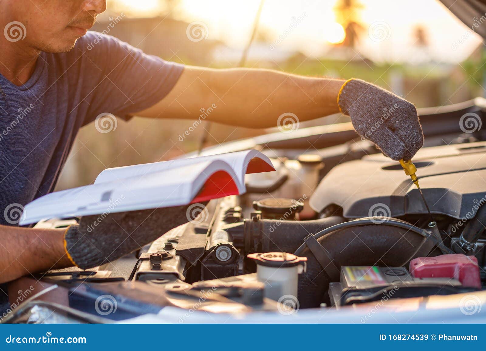 asian man holding and reading the car user manual or user instruction to checking or fixing engine of modern car