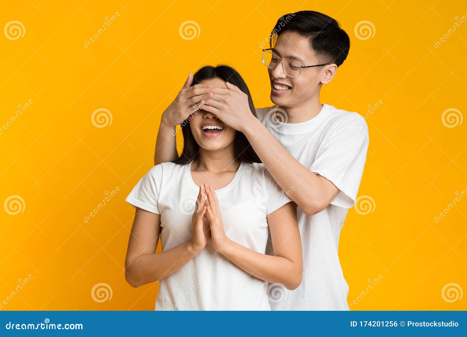 asian-man-standing-behind-his-girlfriend-closing-her-eyes-happy-couple-playing-hide-seek-wife-yellow-background-174201256.jpg