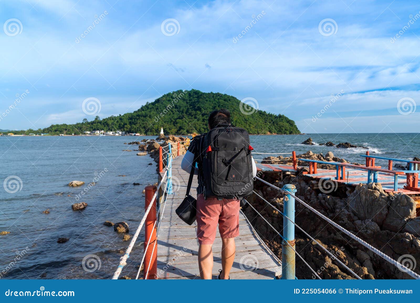 asian man tourist backpaker walking on wooden bridge with rope rail bridge to viewpoint to see white pagoda on the stone in the