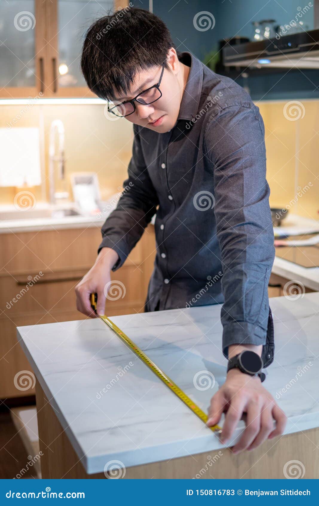 Asian Man Using Tape Measure On Kitchen Counter Stock Image