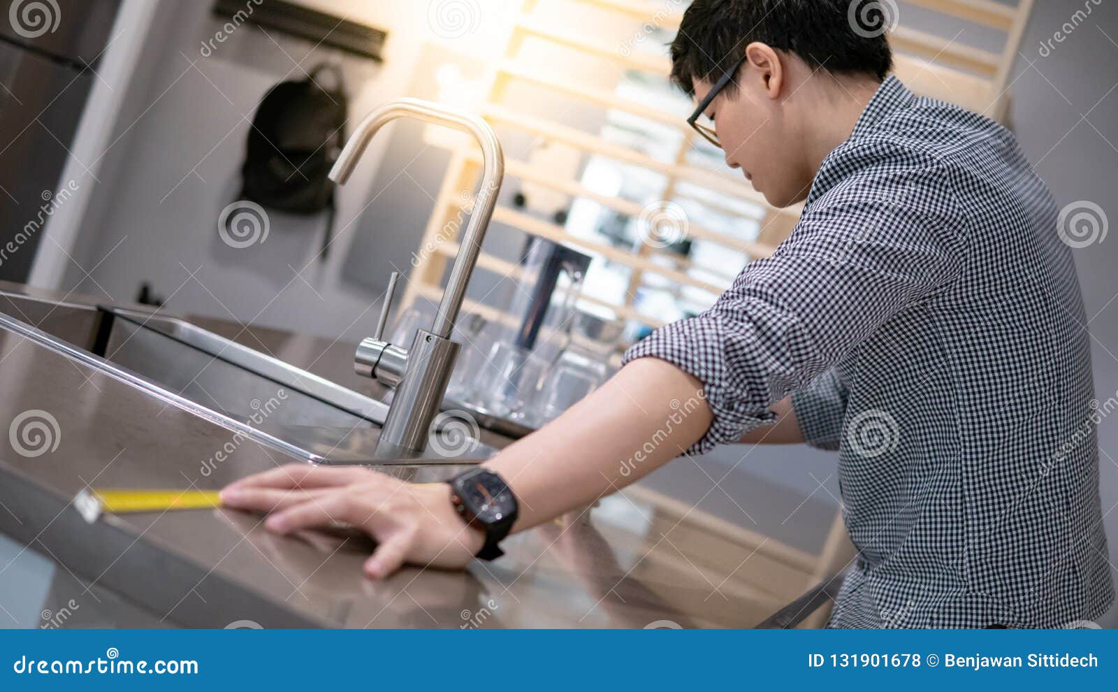 Asian Man Using Tape Measure On Kitchen Counter Stock Photo
