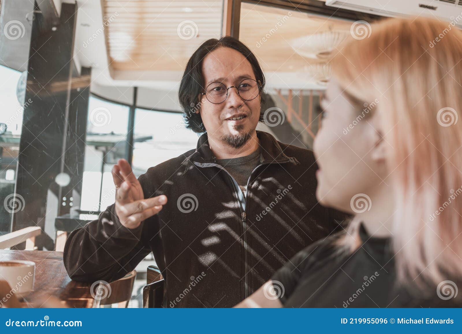 an asian mentor or supervisor instructs and teaches a younger asian woman protege. casual discussion at a coworking space