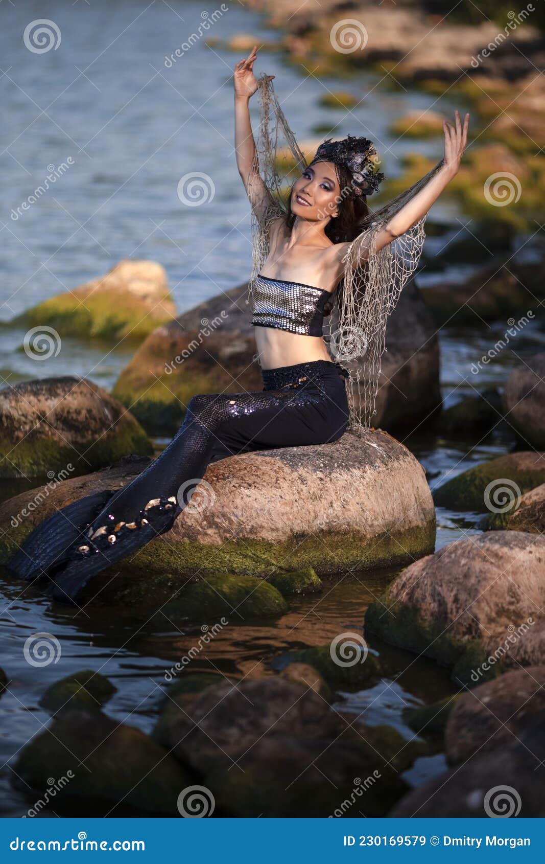 Asian Mermaid with Net at Sea Coast on Rocks while Wearing