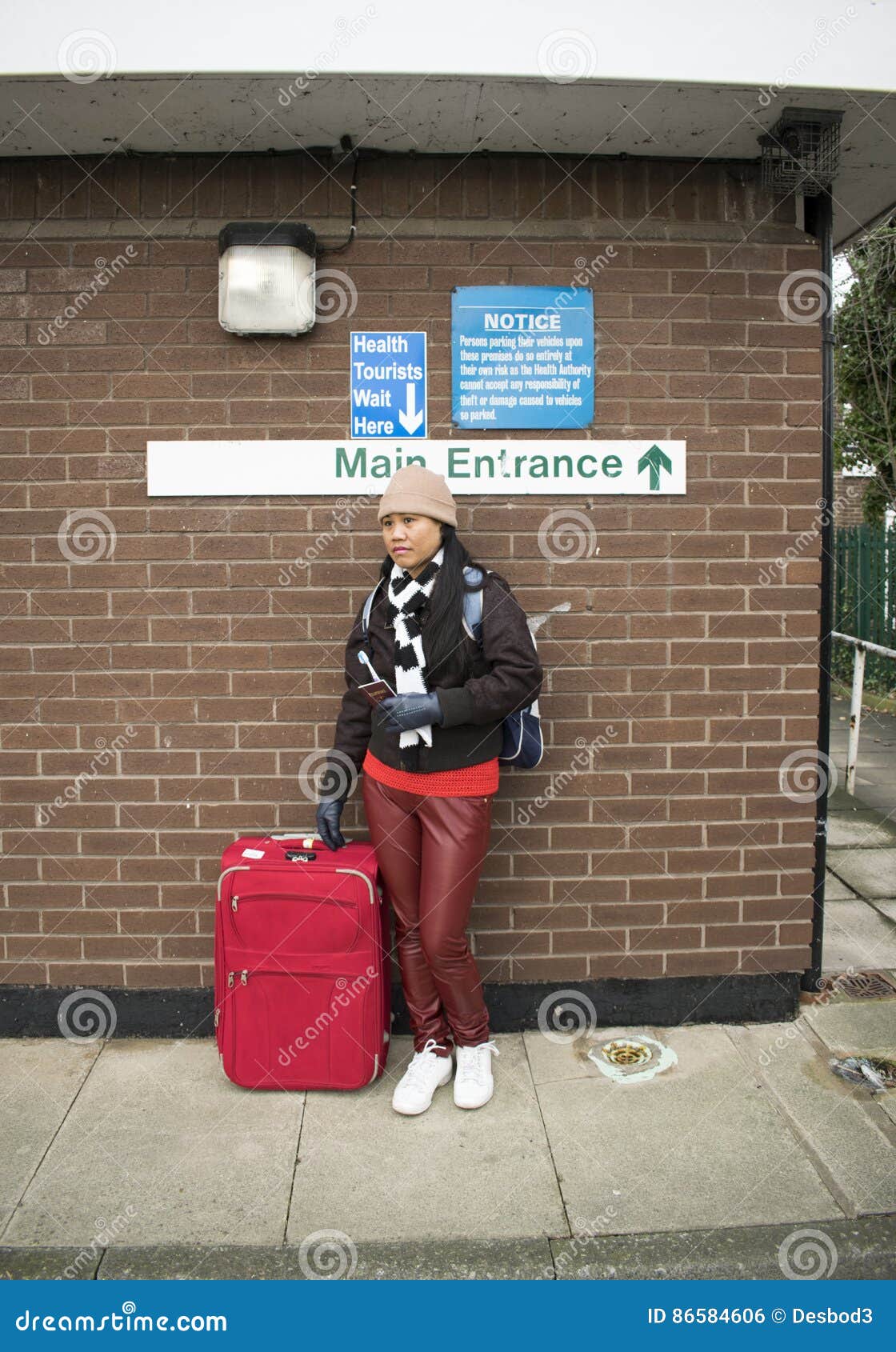 asian nhs health tourist with sign above