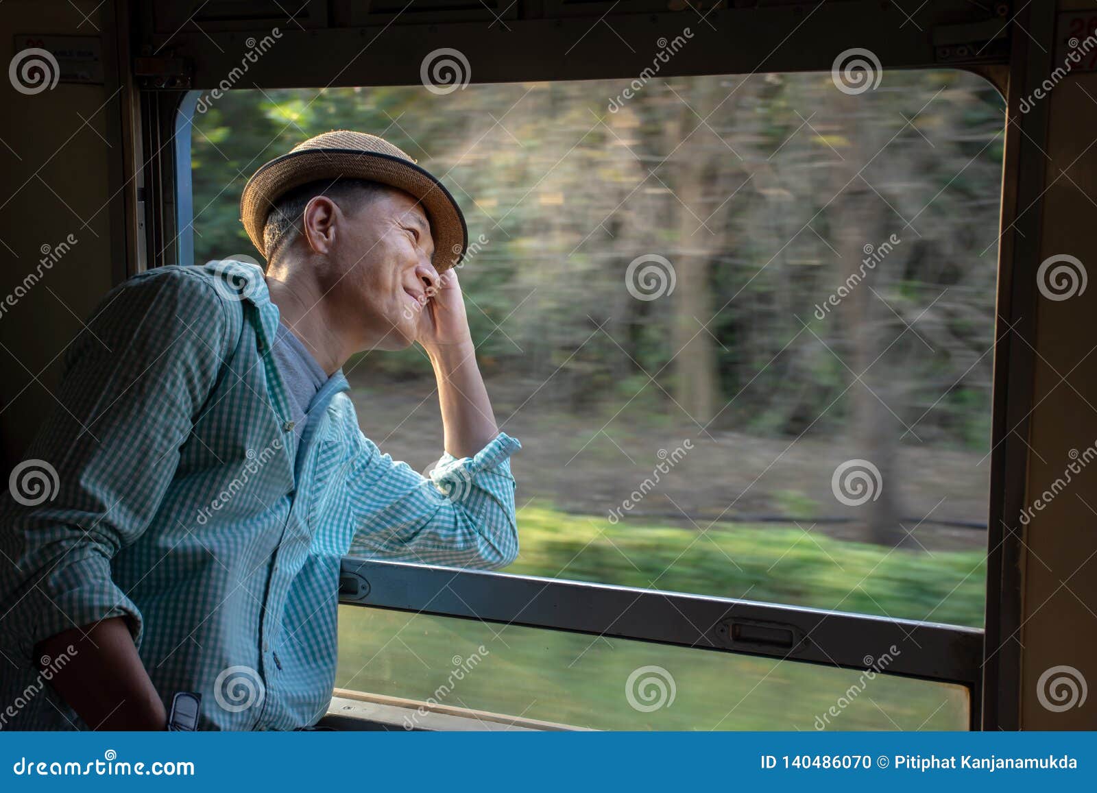 asian passenger wearing hat looking out of train window