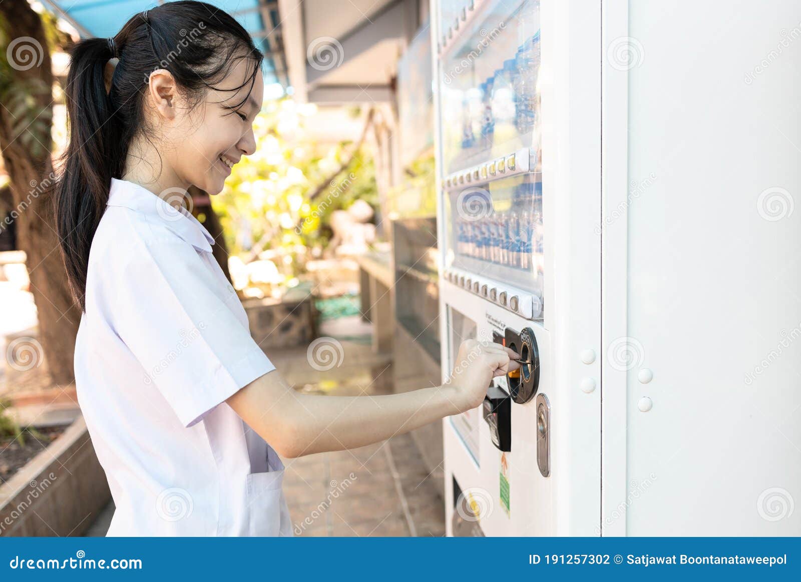 asian people paying or buying hygienic drinking water from automatic vending machine in area lacking clean water,student inserting