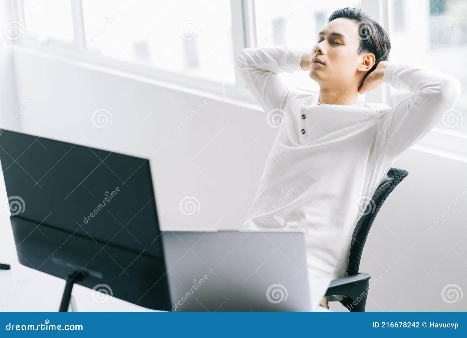 asian programmer sits with his head back in his chair to relax after a tiring working time