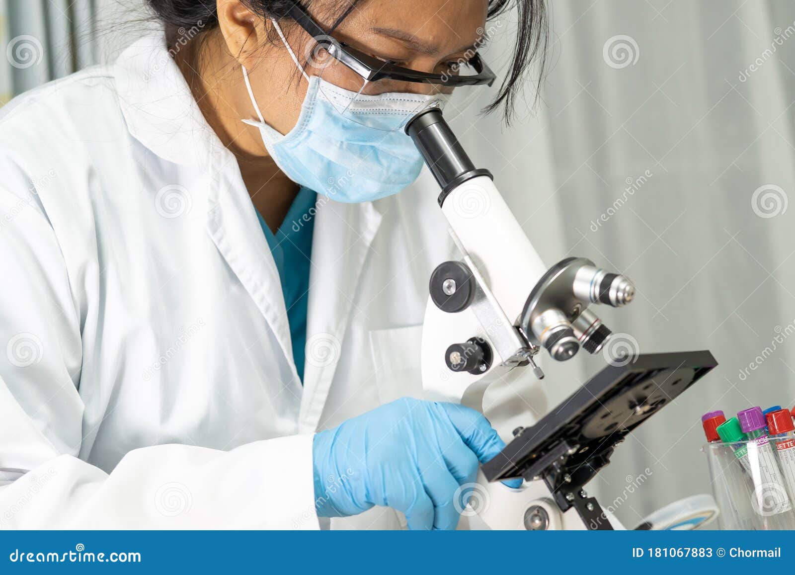 asian scientist biochemist or microbiologist working research with a microscope in laboratory.