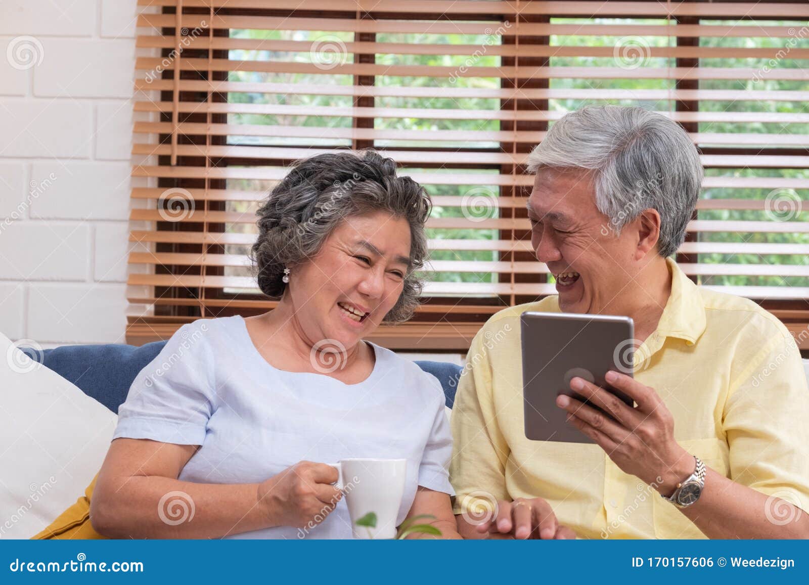 asian senior couple using table compute and drink coffee sitting at sofa in living room at home.senior with technology lfiestyle.a