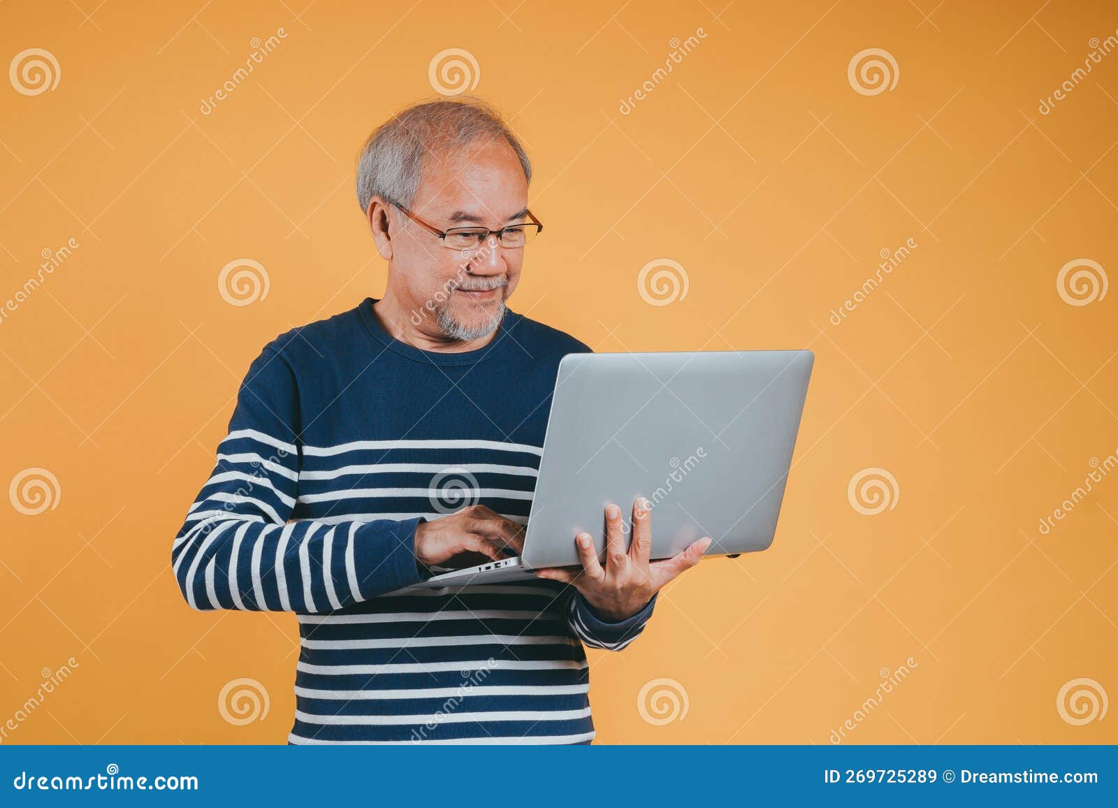 Asian Senior Man Using Laptop Computer for Working after Retirement on the Yellow Background