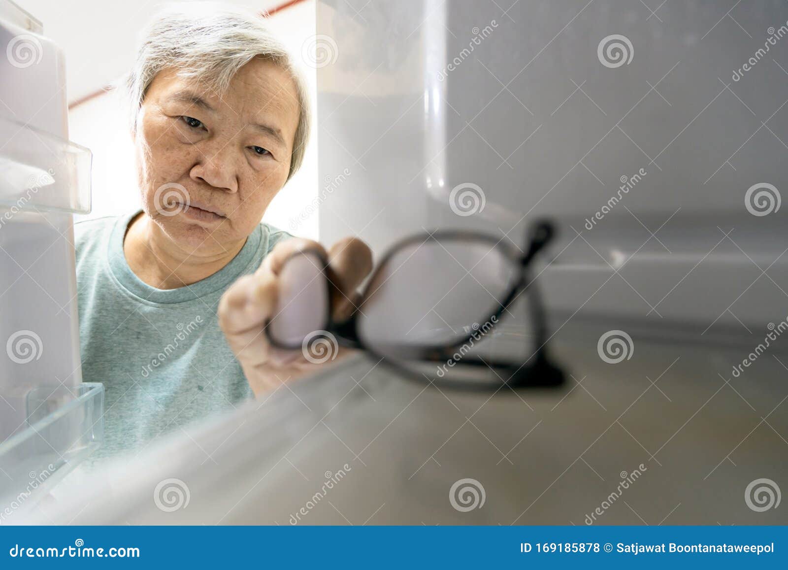 asian senior woman with memory impairment symptoms,forget her glasses in the refrigerator or storing glasses in the fridge,female