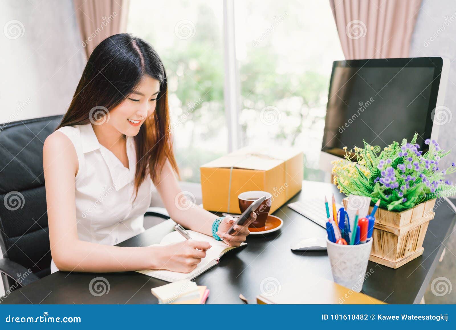 asian small business owner work at home office, using mobile phone call, writing confirm purchase order on notebook