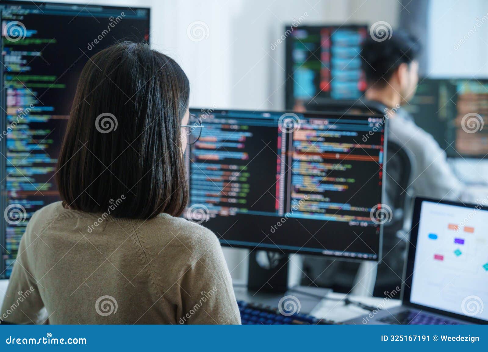 asian software developers working on multiple screens displaying code and application diagrams in a modern office