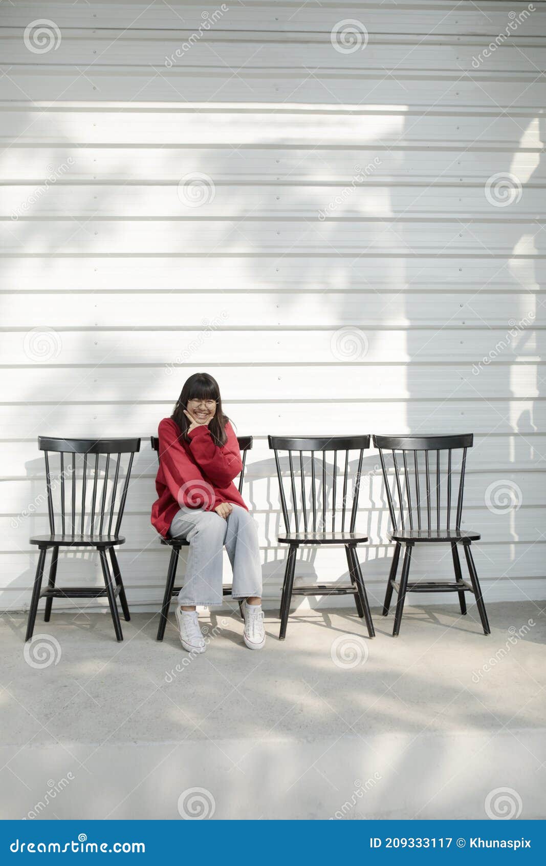 asian teenager sitting on wood desk against white wall background