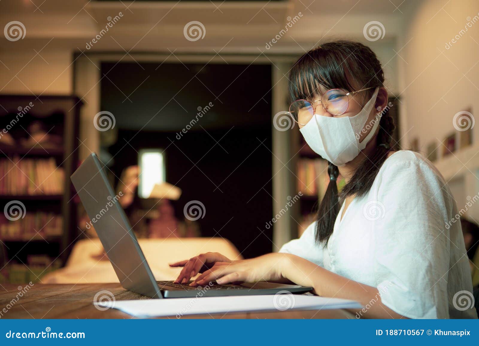 asian teenager wearing protection mask quarantine at home and  working on computer laptop