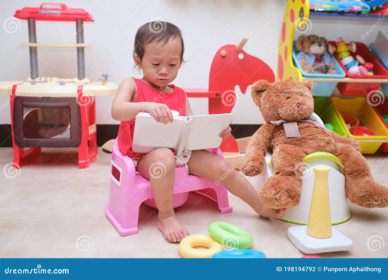 Asian Toddler Girl Child Sitting on Potty and Reading a Book with Toys ...