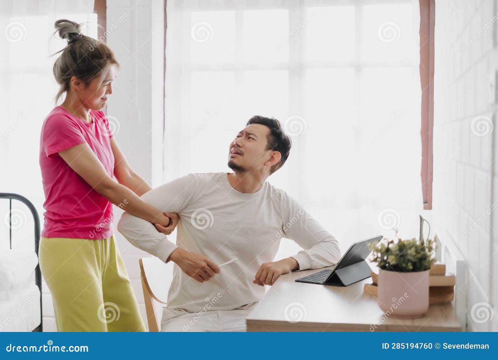  A wife asks her husband about his salary in a respectful and understanding manner while he is working on his tablet.