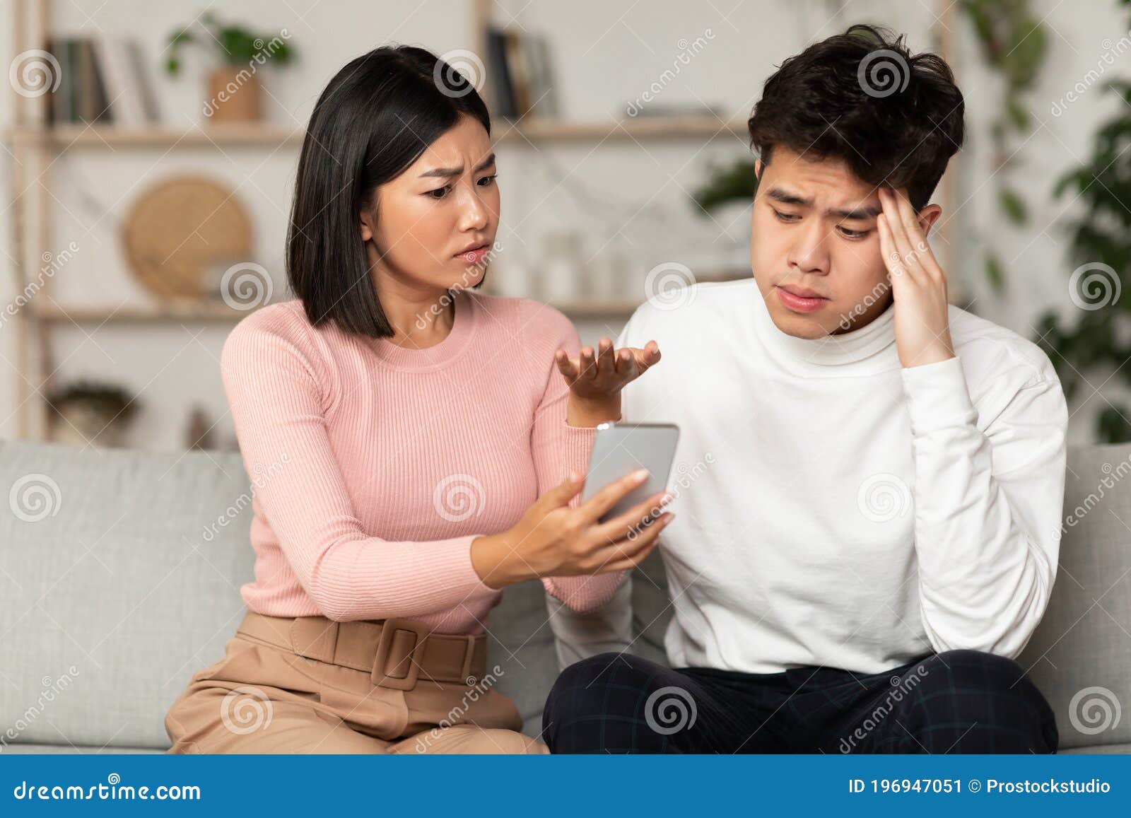 Asian Wife Showing Cheating Husband His Phone Suspecting Affair Indoors