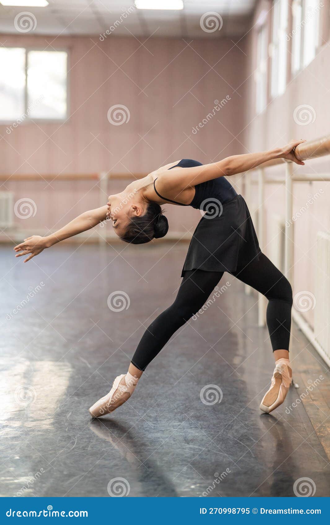 Asian Woman Doing Back Flexibility Exercises at the Ballet Barre