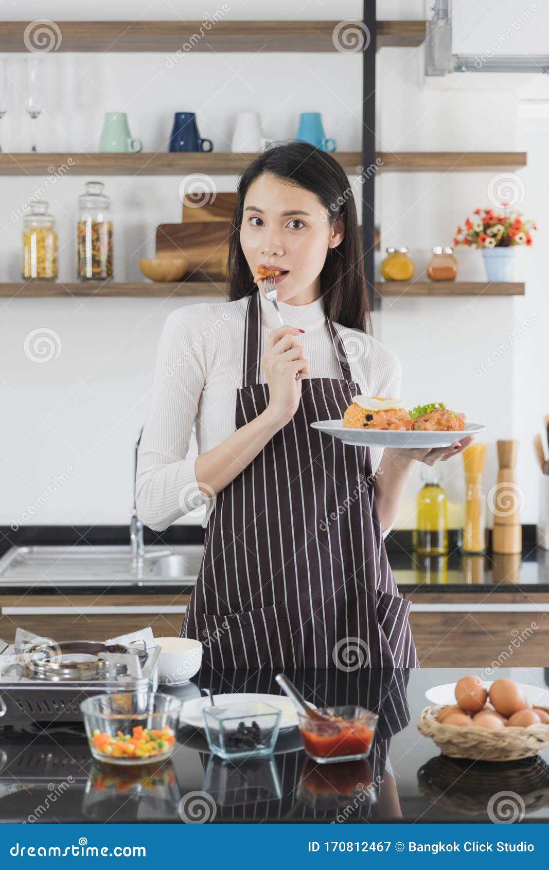 Asian Woman Eating Fried Rice In Kitchen Stock Image - Image of food