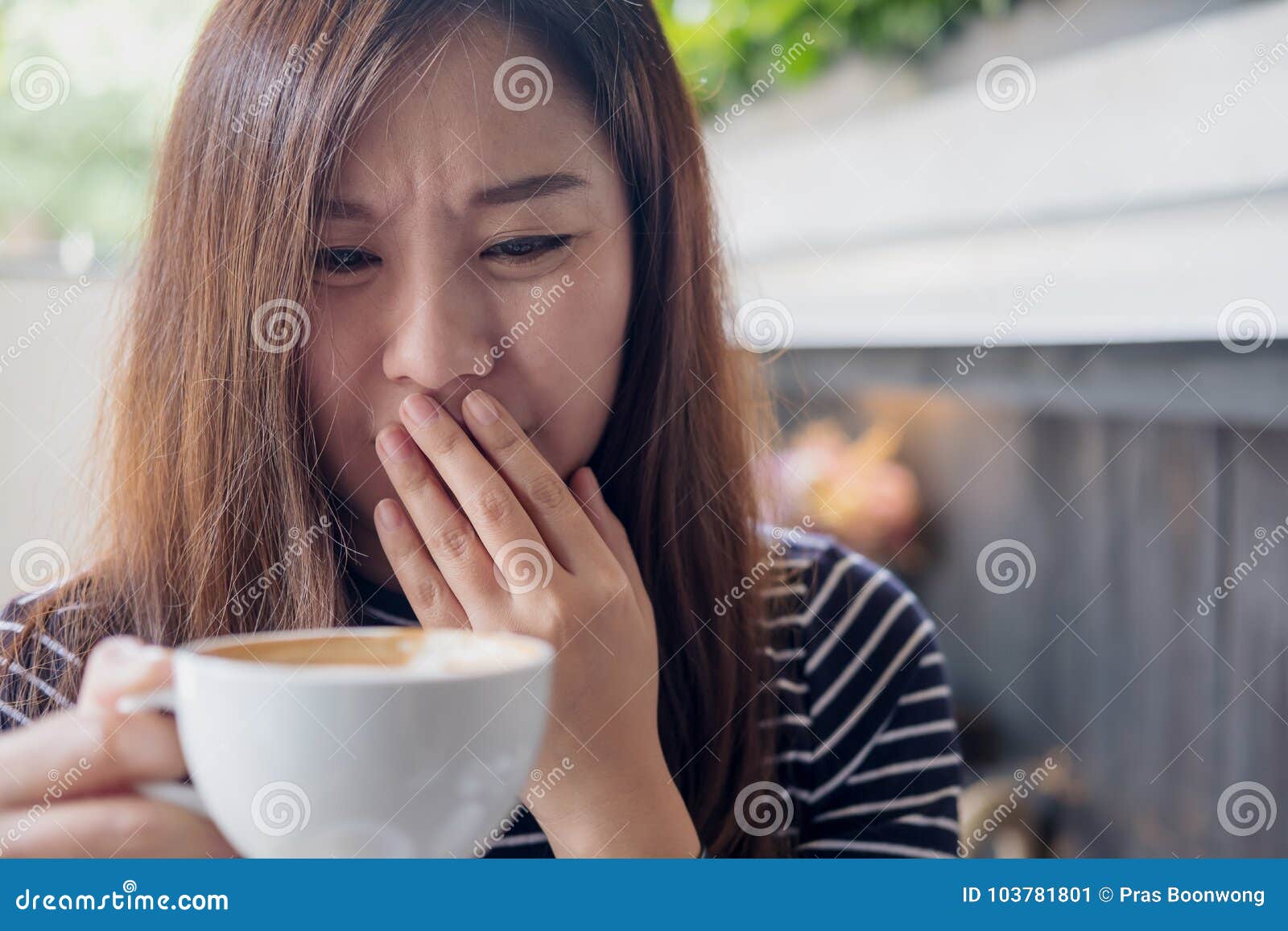 asian woman holding hot coffee with feeling strange and smelling bad in coffee shop