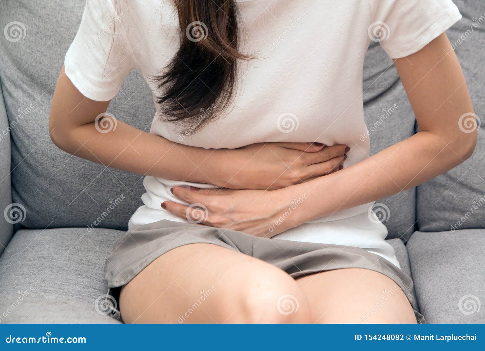 asian woman holds her stomach with both hands. stomach upset or pain during menstruation.