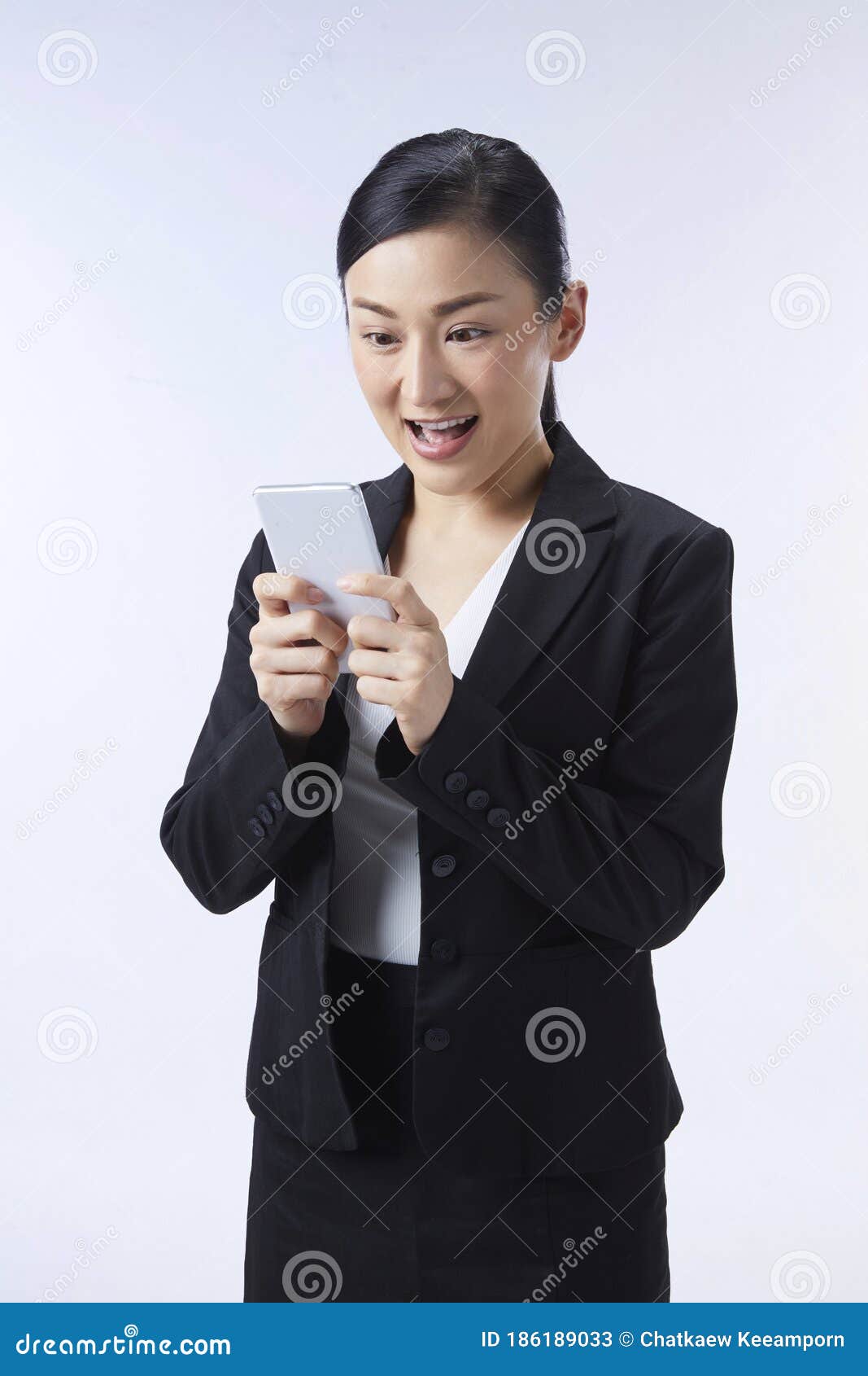 an asian woman looking at her mobile phone very gladly. business ideas, job applications, good news, selection, finalists