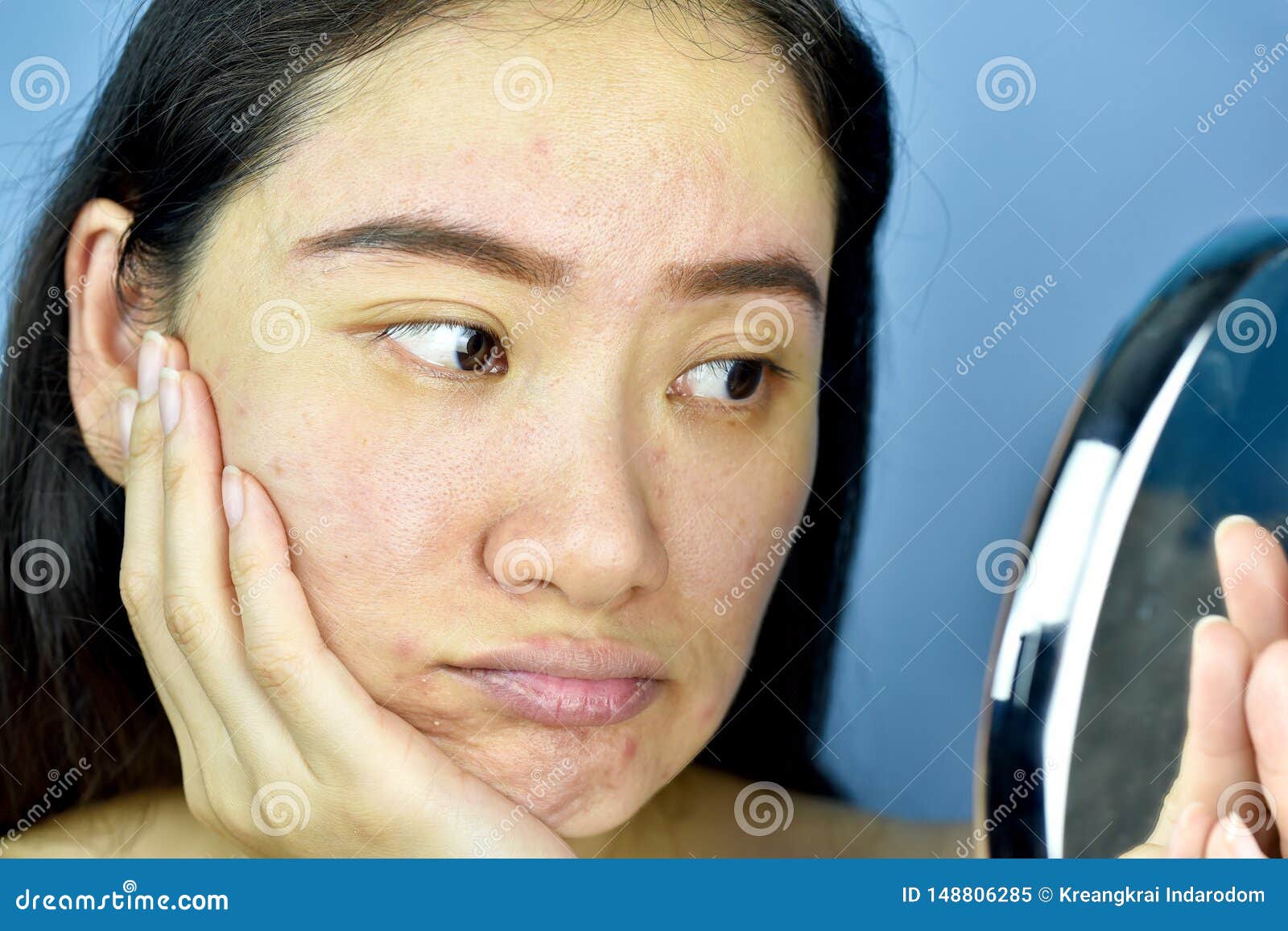asian woman looking at herself in the mirror, female feeling annoy about her reflection appearance show the aging facial skin sign