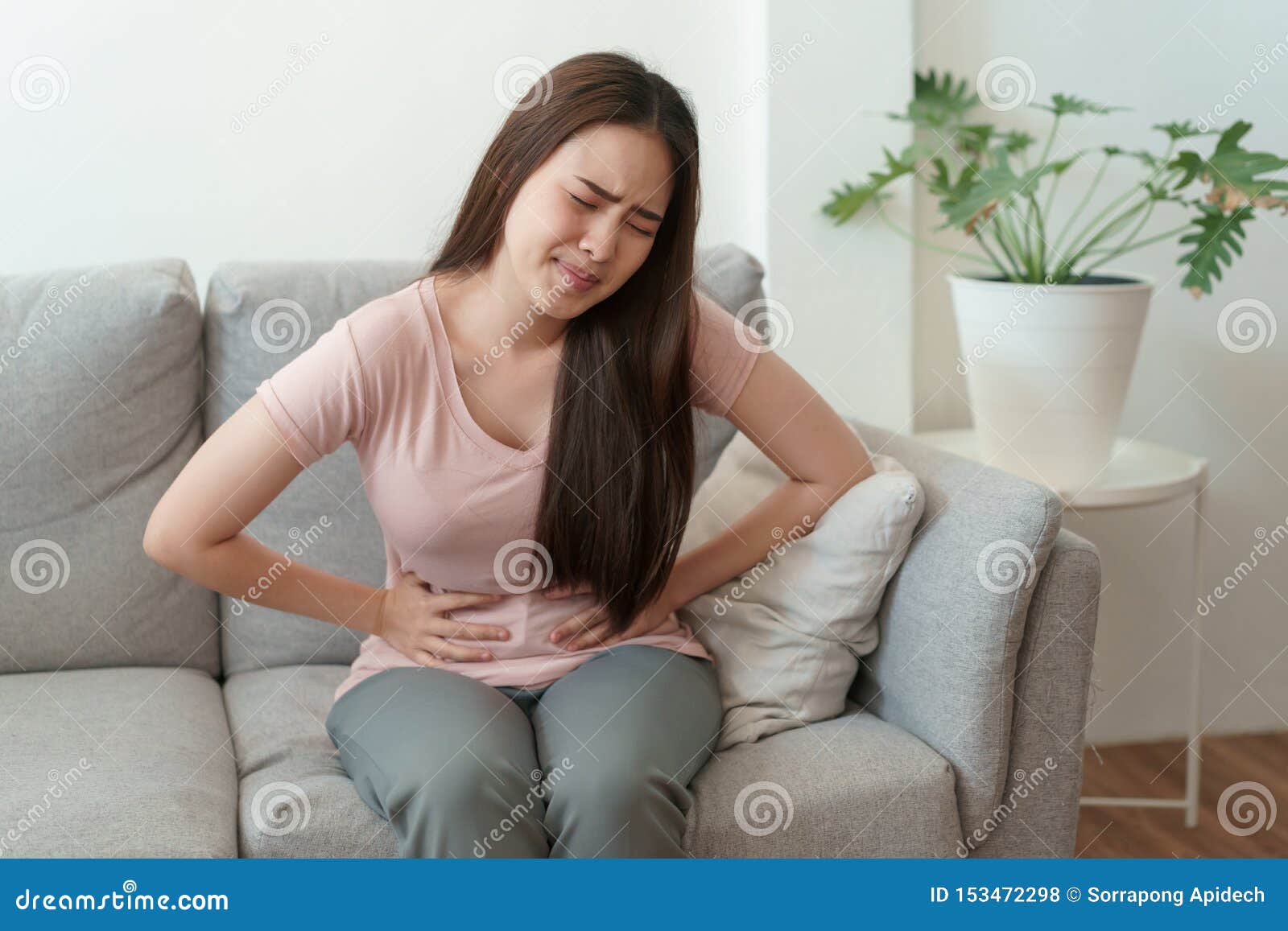 asian woman with menstruation and pain period cramps. young women having painful sitting on sofa at her home