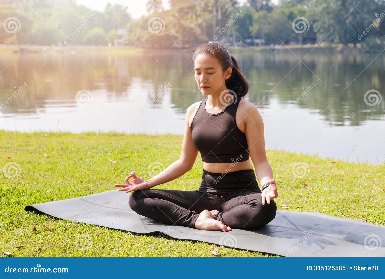 asian woman practicing yoga in root bond, mula bandha pose on the mat in outdoor park