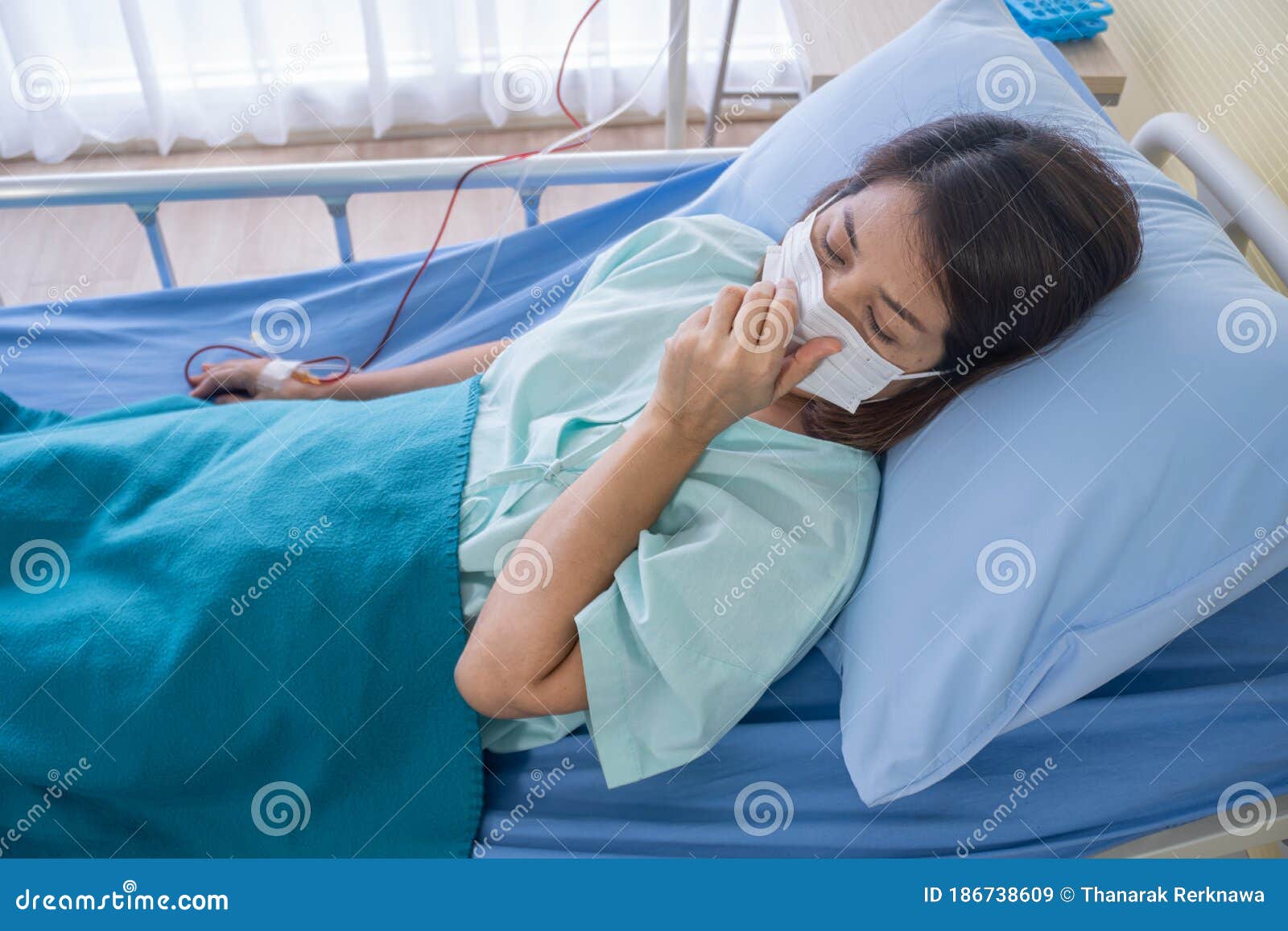 asian woman is sick has a high fever, sneezing, is recuperating in the patient`s dress lay on the patient bed in the hospital wit