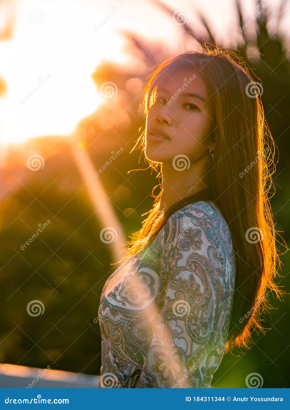 Asian Woman With Tanned Beauty Skin Portrait In A Green Garden With Sun