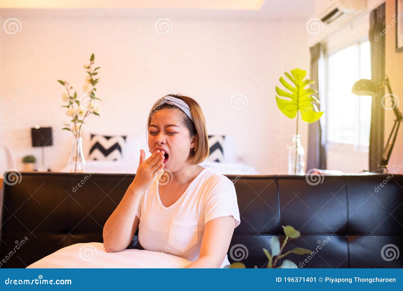 asian woman yawning during sitting on sofa and tired sleepy,female with symptoms sleepiness