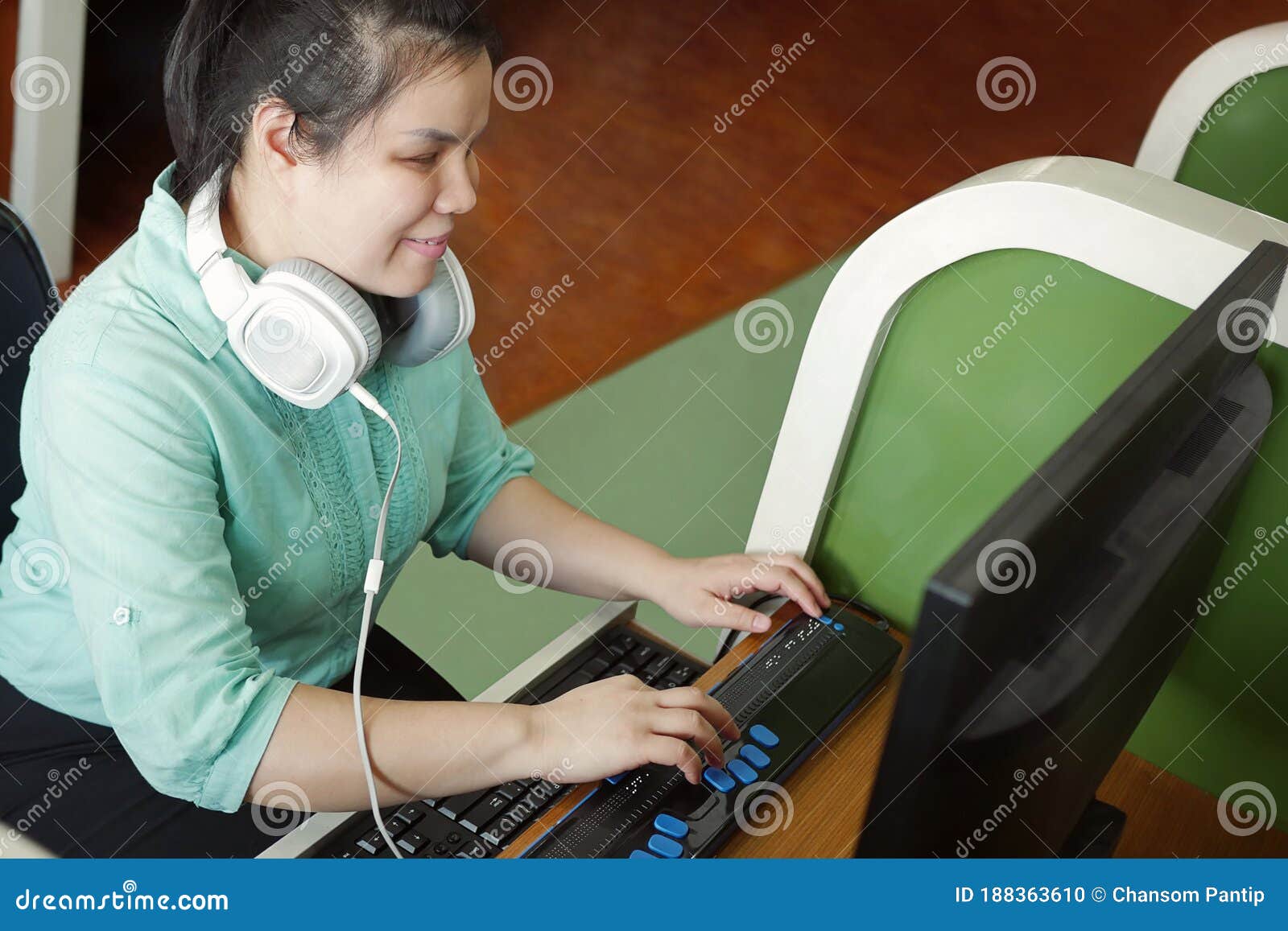 asian young blind woman with headphone using computer with refreshable braille display or braille terminal a technology device for