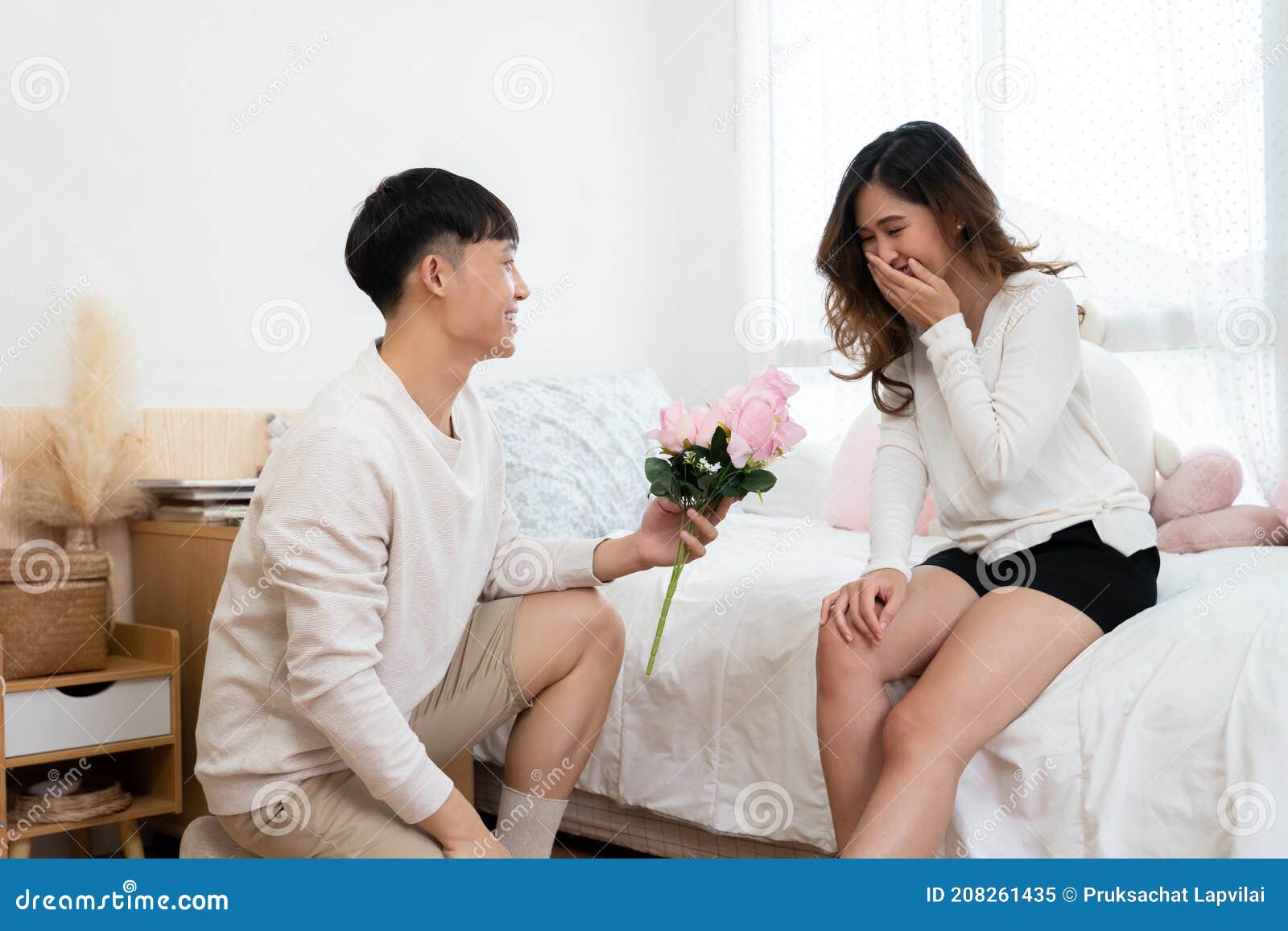 Asian Young Man Kneeling and Giving a Bouquet of Pink Flowers To His Girlfriend Stock Image